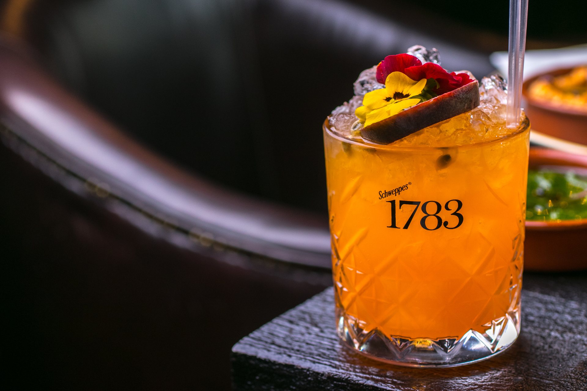 A tall cocktail with mint and dried citrus at the bar